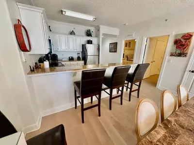 a kitchen with a group of chairs around a table at Tropic Winds 1201 in Panama City Beach