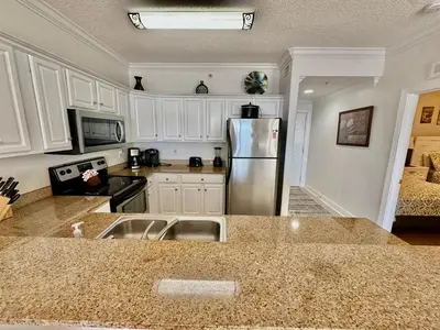 a kitchen with a stainless steel refrigerator and white cabinets at Tropic Winds 1201 in Panama City Beach
