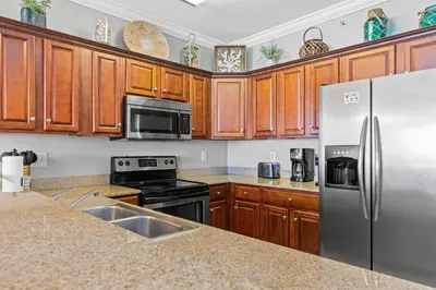 a kitchen with wooden cabinets and a stainless steel refrigerator at Tropic Winds 605 in Panama City Beach
