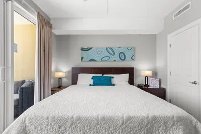 a bedroom with a bed with a blue pillow on it at Tropic Winds 605 in Panama City Beach