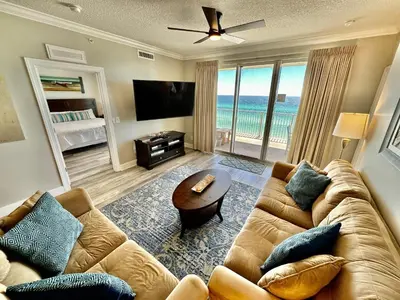 a living room with a couch and a table and a television at Tropic Winds 605 in Panama City Beach