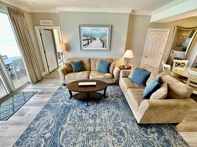 a living room with two couches and a table at Tropic Winds 605 in Panama City Beach