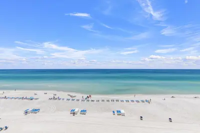 a beach with a group of chairs and the ocean at Tropic Winds 605 in Panama City Beach