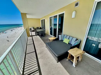 a balcony with a bed and a table and the beach at Tropic Winds 605 in Panama City Beach