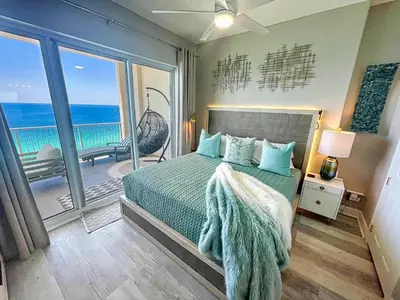 a bedroom with a bed and a balcony with the ocean at Ocean Reef 2204 in Panama City Beach