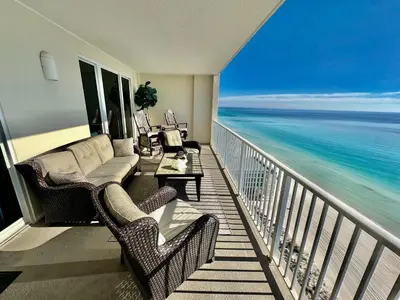 a balcony with a couch and chairs and the ocean at Ocean Reef 1705 in Panama City Beach
