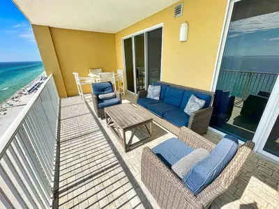a balcony with a couch and chairs and the ocean at Tropic Winds 1706 in Panama City Beach