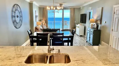 a kitchen and living room with a sink and a table at Tropic Winds 904 in Panama City Beach