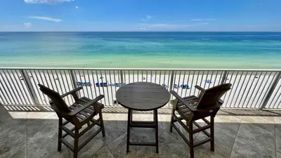 a table and two chairs on a balcony with the ocean at Tropic Winds 904 in Panama City Beach