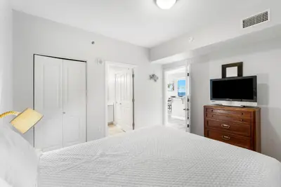a white bedroom with a bed and a tv on a dresser at Shores Of Panama #2101 in Panama City Beach