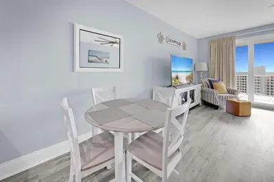 a dining room with a table and chairs and a living room at Laketown Wharf 1120 by Emerald Coast Retreats in Panama City Beach