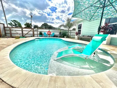 a swimming pool with a chair and an umbrella at 2 Fins Up, Beach Home, Private Pool , Golf Cart, 6 beds in Panama City Beach
