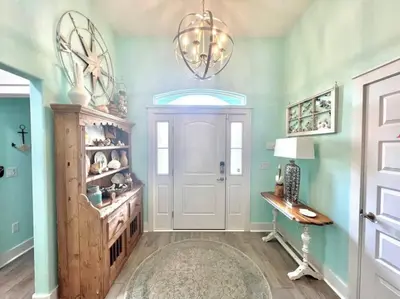 a hallway with a door and a table and a chandelier at 2 Fins Up, Beach Home, Private Pool , Golf Cart, 6 beds in Panama City Beach