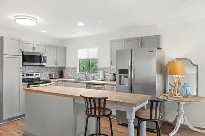 a kitchen with white cabinets and a counter with bar stools at Nest & Nook, Hot Tub, Fire pit, Deck, Yard, close to lake in Panama City Beach