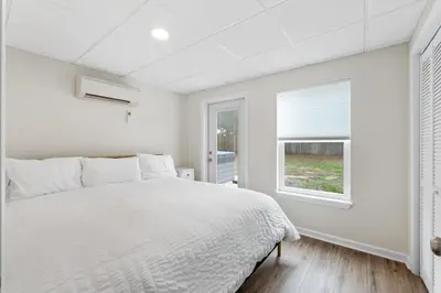 a white bedroom with a bed and a window at Nest & Nook, Hot Tub, Fire pit, Deck, Yard, close to lake in Panama City Beach