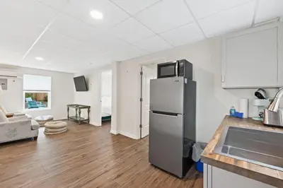 a kitchen with a refrigerator and a living room at Nest & Nook, Hot Tub, Fire pit, Deck, Yard, close to lake in Panama City Beach