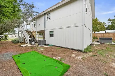 a house with a green lawn in front of it at Nest & Nook, Hot Tub, Fire pit, Deck, Yard, close to lake in Panama City Beach
