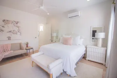 a white bedroom with a white bed and a chair at POOL | Heart & Soul Luxury | Walk to Beach in Inlet Beach