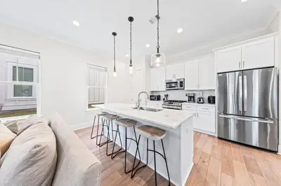a kitchen with white cabinets and a kitchen island with bar stools at Walk to Beach! Sleeps 18 - 10 beds in Rosemary Beach