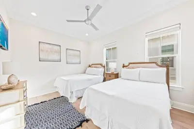 a white bedroom with two beds and two windows at Walk to Beach! Sleeps 18 - 10 beds in Rosemary Beach