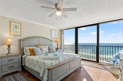 a bedroom with a bed and a balcony with the ocean at Beach Haven! 2BR 2BA Sleeps 6! Coastal paradise awaits! in Panama City Beach