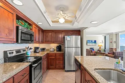 a kitchen with wooden cabinets and a stainless steel refrigerator at Beach Haven! 2BR 2BA Sleeps 6! Coastal paradise awaits! in Panama City Beach