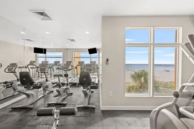 a gym with treadmills and chairs and a view of the beach at 707 Sterling Reef in Panama City Beach