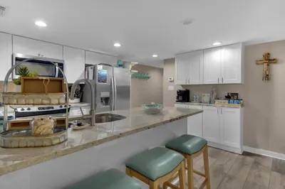 a kitchen with white cabinets and a counter with stools at Sugar Beach C1 in Panama City Beach
