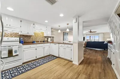 a kitchen with white cabinets and a wooden floor at 9614 Beach Blvd in Panama City Beach