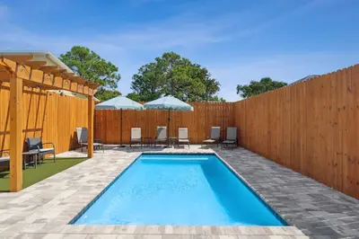 a swimming pool in a fence with chairs and umbrellas at Grand Retreat I! 4BR 5BA Sleeps 15! Private Pool! Luxury and comfort await! in Panama City Beach