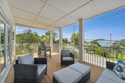 a screened porch with chairs and a couch and a table at Grand Retreat I! 4BR 5BA Sleeps 15! Private Pool! Luxury and comfort await! in Panama City Beach