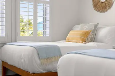a white bedroom with two beds and a window at Modern Beach Haüs 4 min walk to beach w/ pool BBQ in Panama City Beach