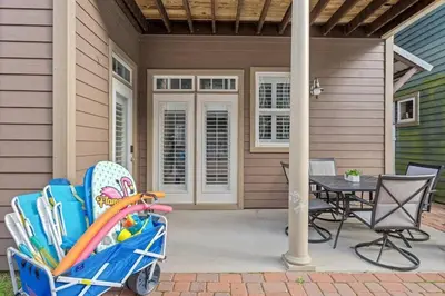 a patio with a table and chairs and a cart with umbrellas at Modern Beach Haüs 4 min walk to beach w/ pool BBQ in Panama City Beach