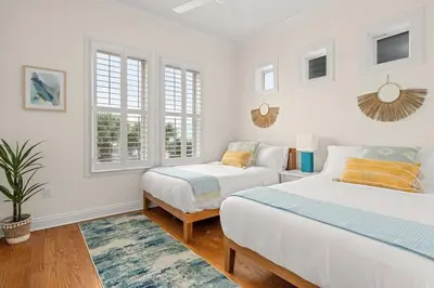 two beds in a room with white walls and windows at Modern Beach Haüs 4 min walk to beach w/ pool BBQ in Panama City Beach