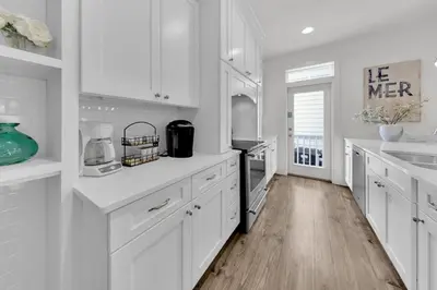 a white kitchen with white cabinets and a wooden floor at The Java House in Rosemary Beach