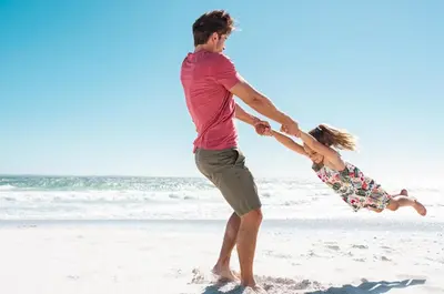 a man and a girl playing in the sand on the beach at Seas The Day in Rosemary Beach