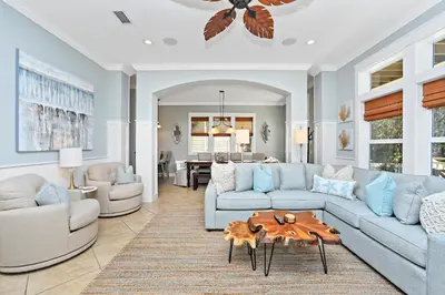 a living room with a blue couch and a table at Pool's Paradise in Rosemary Beach