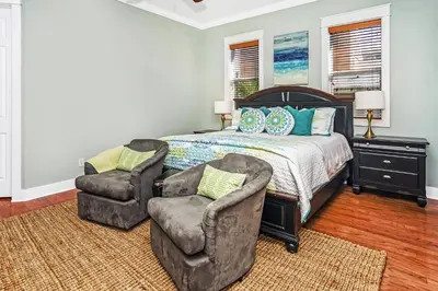 a bedroom with a bed and two chairs at Pool's Paradise in Rosemary Beach