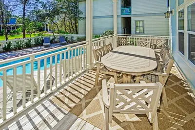 a patio with a table and chairs on a balcony at Pool's Paradise in Rosemary Beach