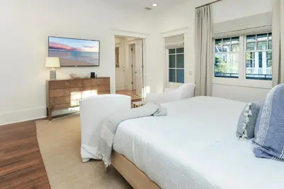 a white bedroom with a bed and a television at Barefoot at the Beach in Watersound Beach