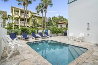 a swimming pool with chairs and a house at My Blue Heaven in Rosemary Beach