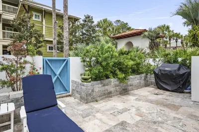 a blue door in a backyard with a retaining wall at My Blue Heaven in Rosemary Beach