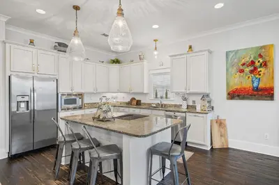 a kitchen with white cabinets and a island with bar stools at Sunny Day in Seagrove Beach
