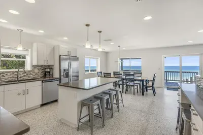 a kitchen with white cabinets and a table with stools at Ashore Thing in Inlet Beach