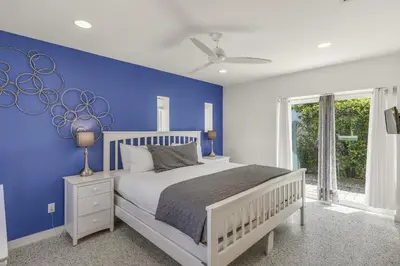 a blue bedroom with a white bed and a blue wall at Ashore Thing in Inlet Beach