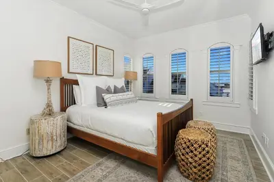 a bedroom with a bed and a chair and windows at B402 Sunset Beach Villa in Inlet Beach