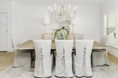 a dining room table with white chairs and a chandelier at B402 Sunset Beach Villa in Inlet Beach
