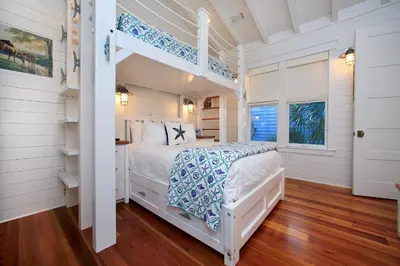 a white bedroom with a bed and a ladder at Pura Vida in Watersound Beach