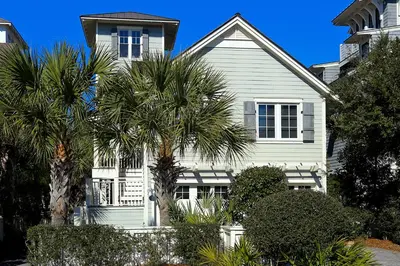 a white house with palm trees in front of it at Pura Vida in Watersound Beach