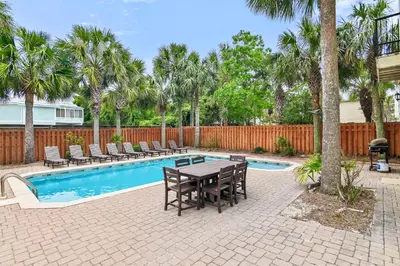 a patio with a table and chairs next to a pool at Buena Vista in Santa Rosa Beach